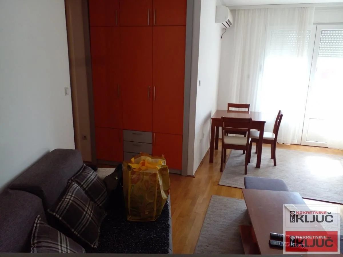 Dnevna soba sa garniturom, trpezarijskim stolom i ugradnim ormanom narandžaste boje.