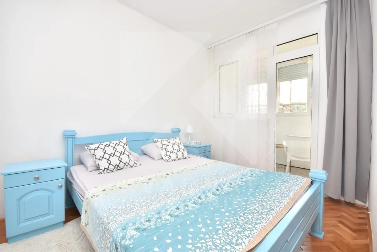 Bedroom with a blue bed and bedside table, and access to the terrace.