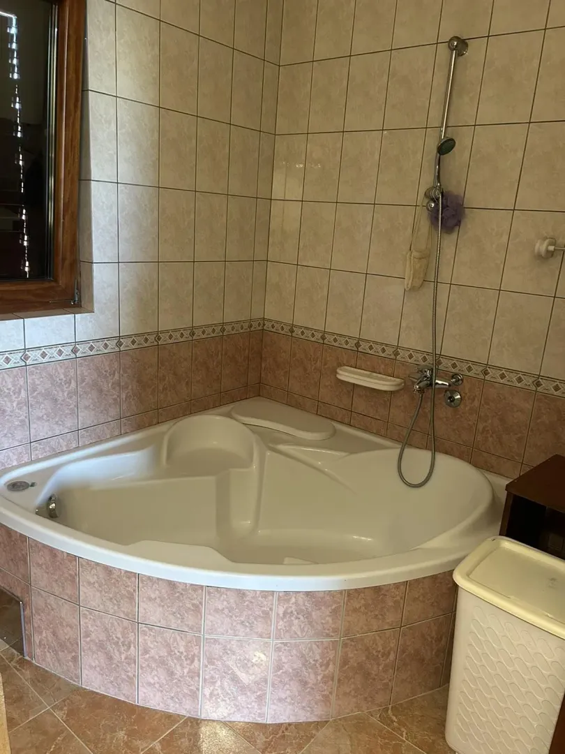 Bathroom featuring a spacious corner bathtub and light tiling.