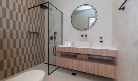 Modern bathroom with a walk-in shower, washbasin, and a round mirror. - image 9