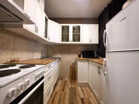 View of a furnished kitchen with white cabinets and a wooden countertop. - image 5