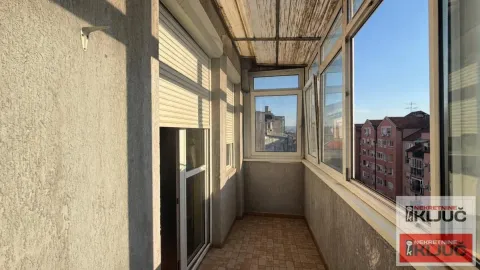 Zastakljeni balkon sa pločicama i pogledom na susedne zgrade. - image 5