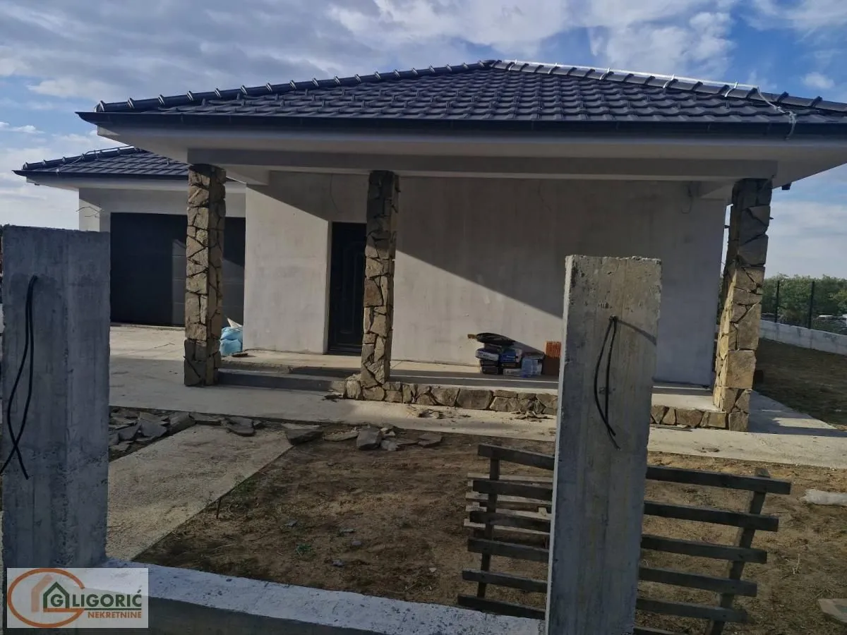 Pogled na eksterijer prizemne kuće sa natkrivenim tremom i kamenim stubovima.