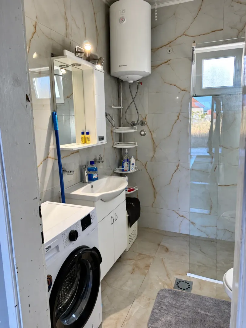 Bathroom equipped with a washbasin, shower enclosure, water heater, and washing machine.