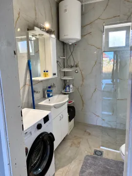 Bathroom equipped with a washbasin, shower enclosure, water heater, and washing machine. - image 7