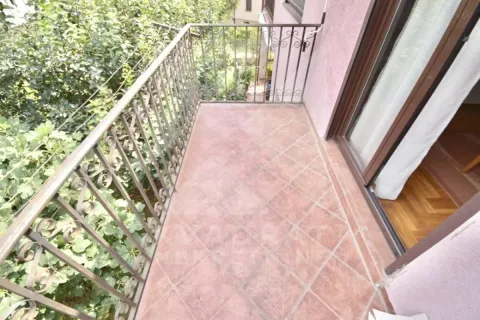 Balcony with tiled flooring and wrought iron railing surrounded by greenery. - image 14
