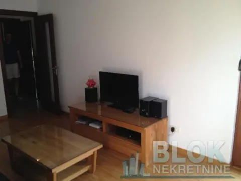 Living room with a wooden coffee table and a TV unit. - image 4