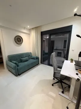 Living room with a green sofa and a desk. - image 11