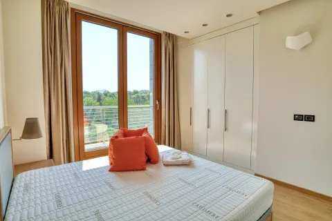 Bright bedroom with a double bed, built-in wardrobe, and balcony doors. - image 15