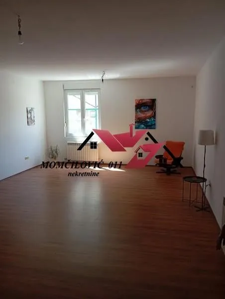 Spacious living room with wooden flooring and a single window.