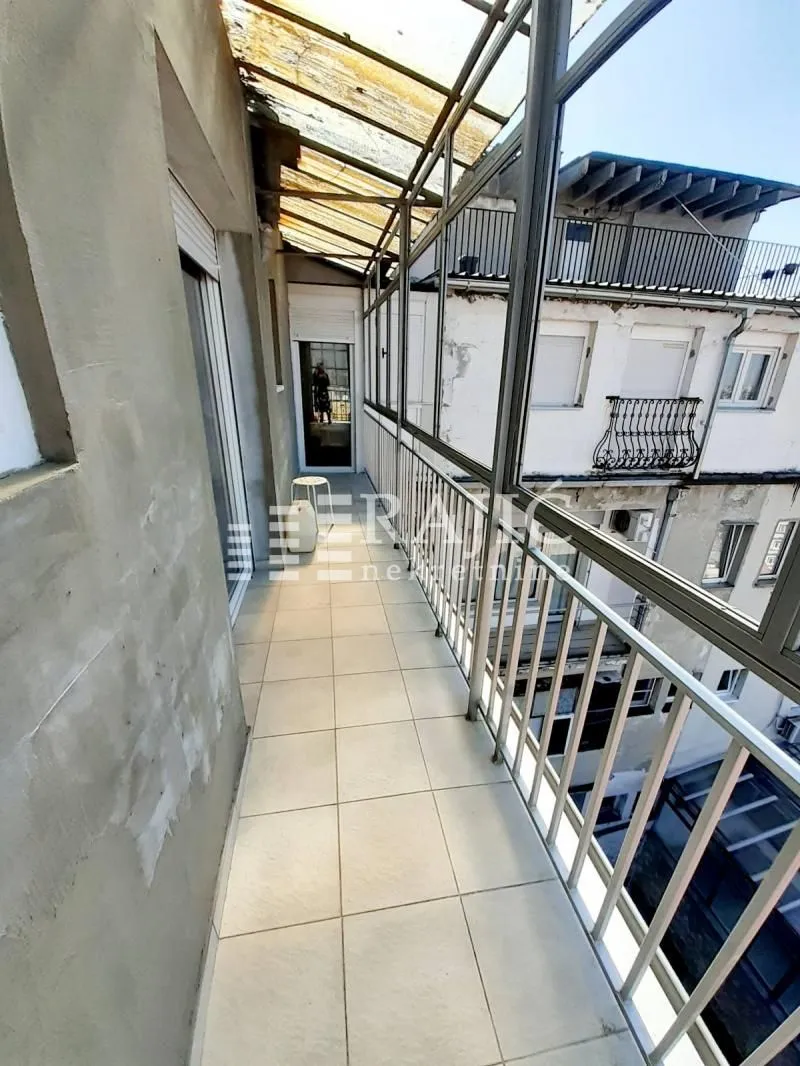 Enclosed balcony with tile flooring and a metal railing.