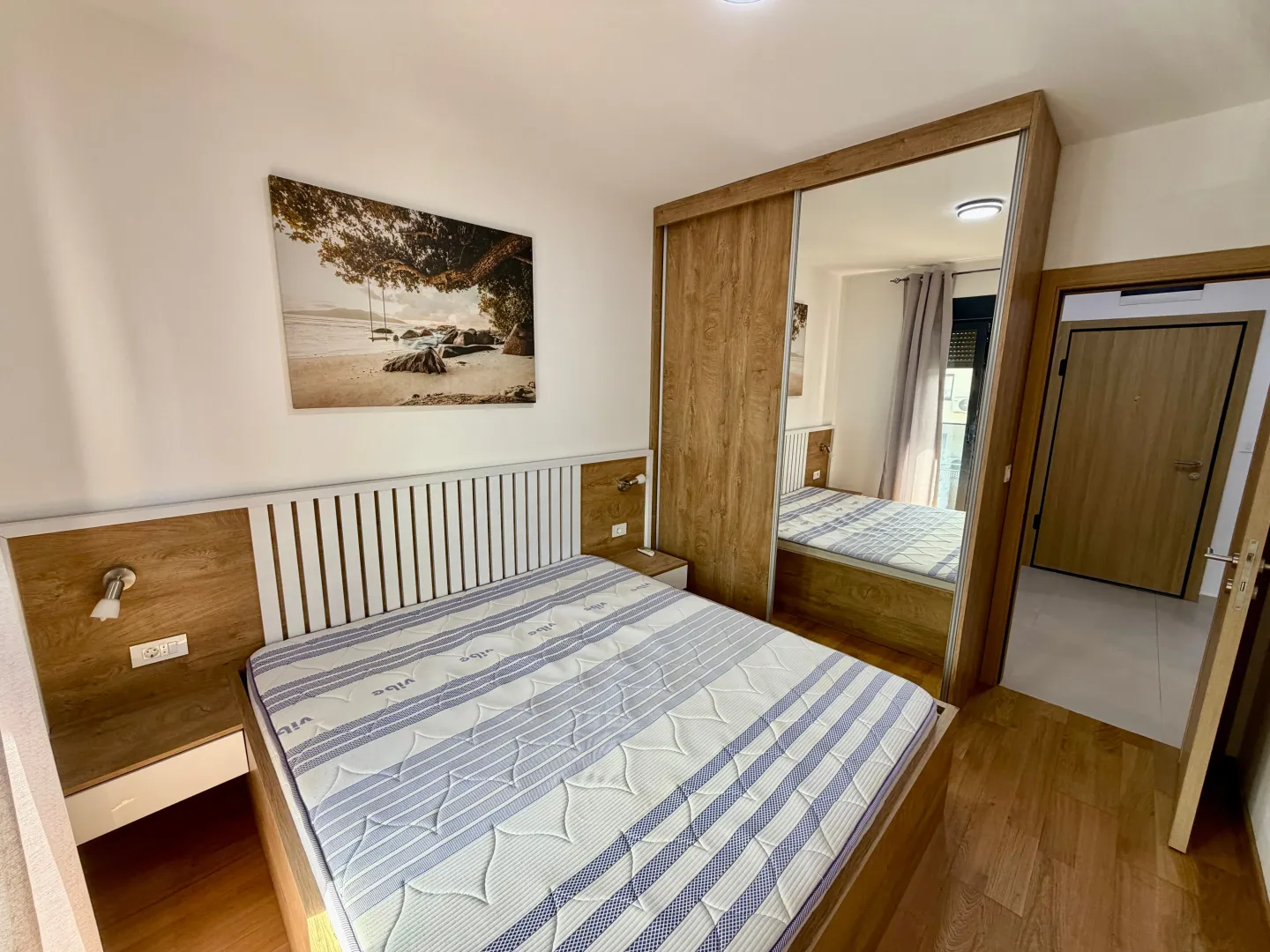Bedroom with a double bed, large mirrored wardrobe, and a picture on the wall.