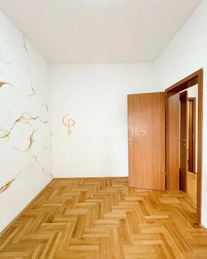 Empty room with parquet flooring and a decorative wall.