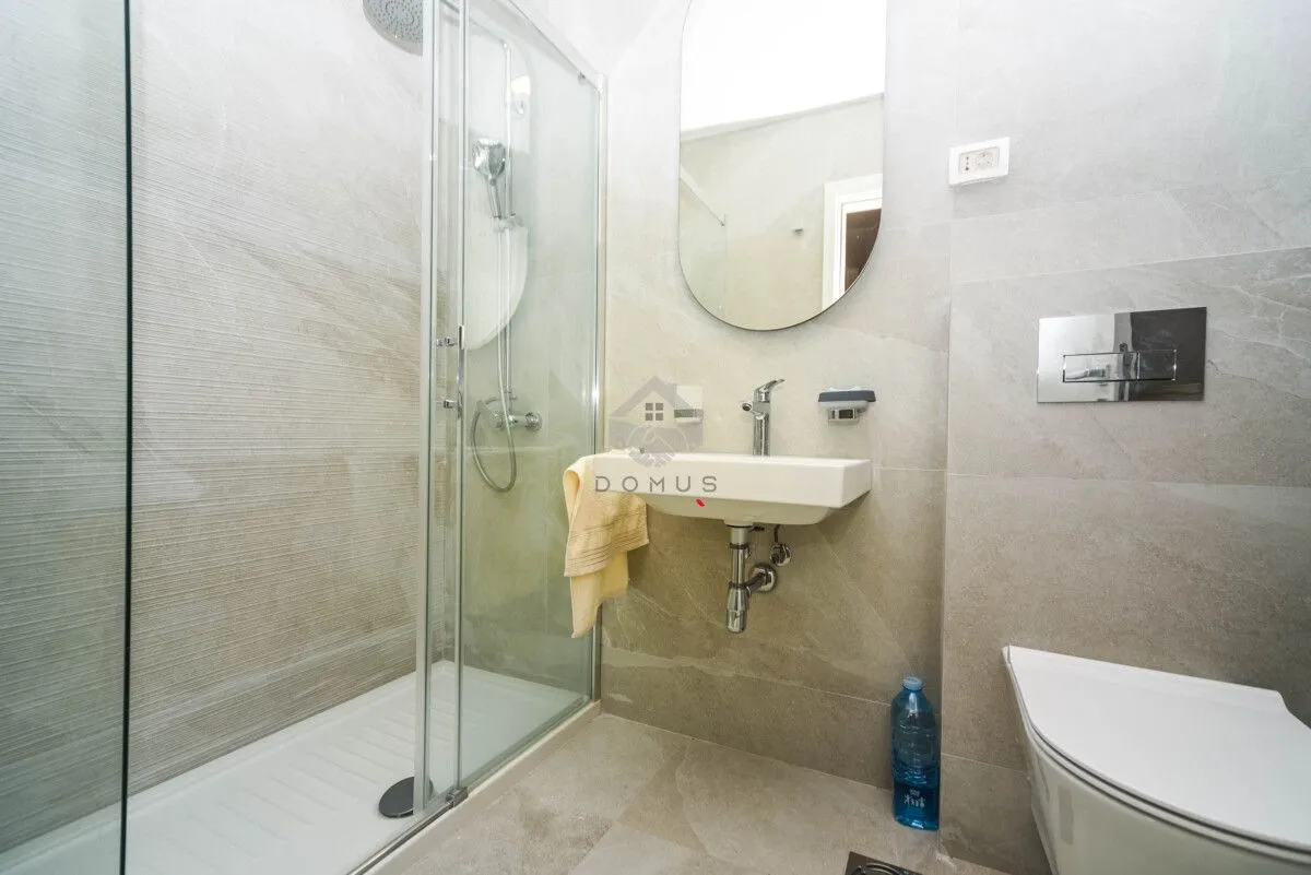 Moderne kupatilo sa tuš kabinom, umivaonikom i ugradnom wc šoljom.