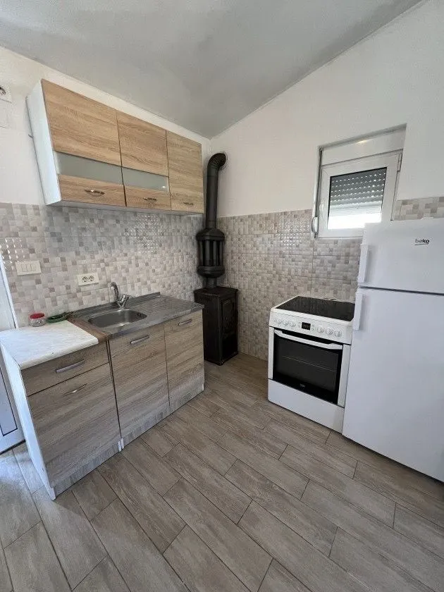 Manja kuhinja sa elementima u boji drveta, šporetom i frižiderom.