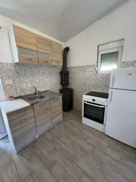 Manja kuhinja sa elementima u boji drveta, šporetom i frižiderom. - image 5
