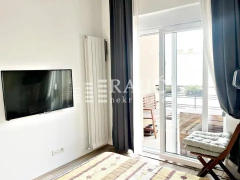 Bedroom with a bed, wall-mounted TV, and access to the terrace. - image 8