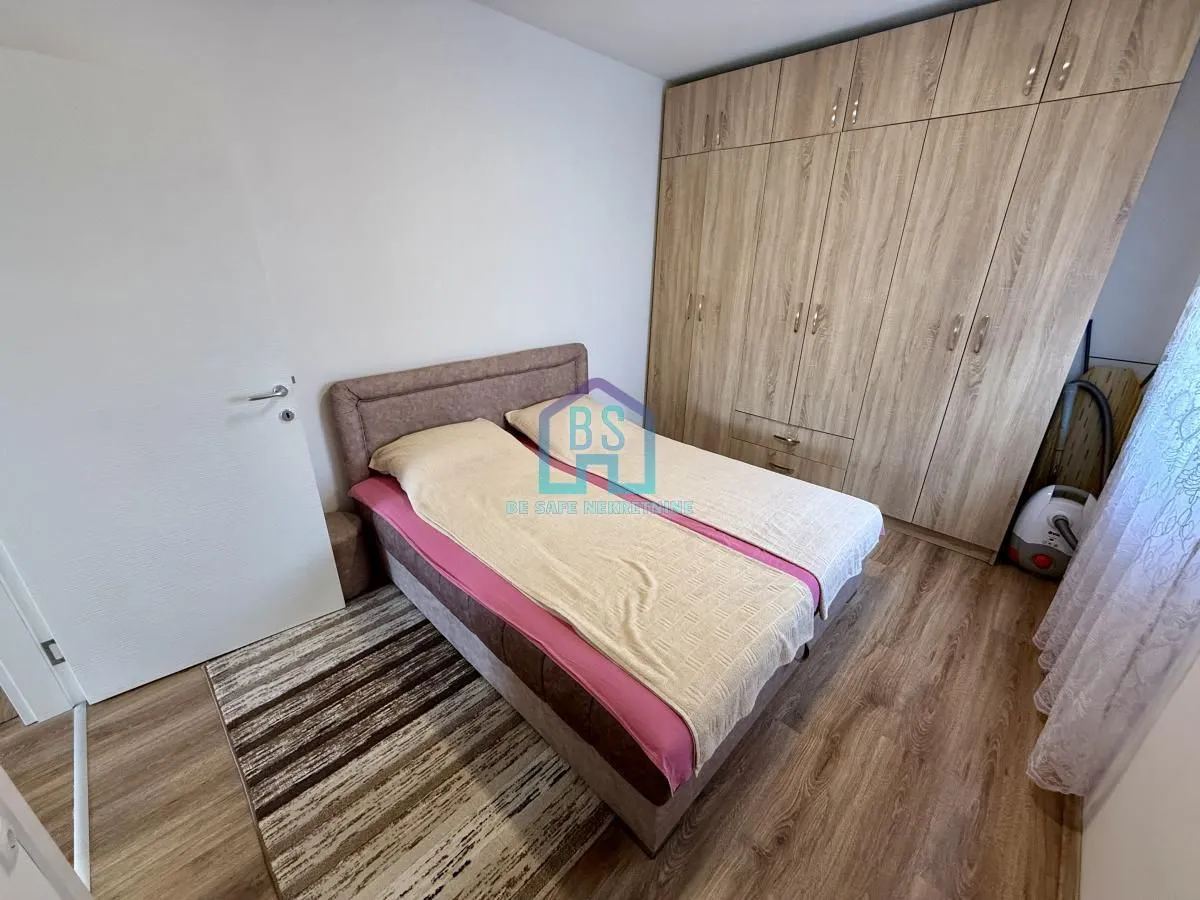 Nameštena spavaća soba sa bračnim krevetom i velikim drvenim ormarom.