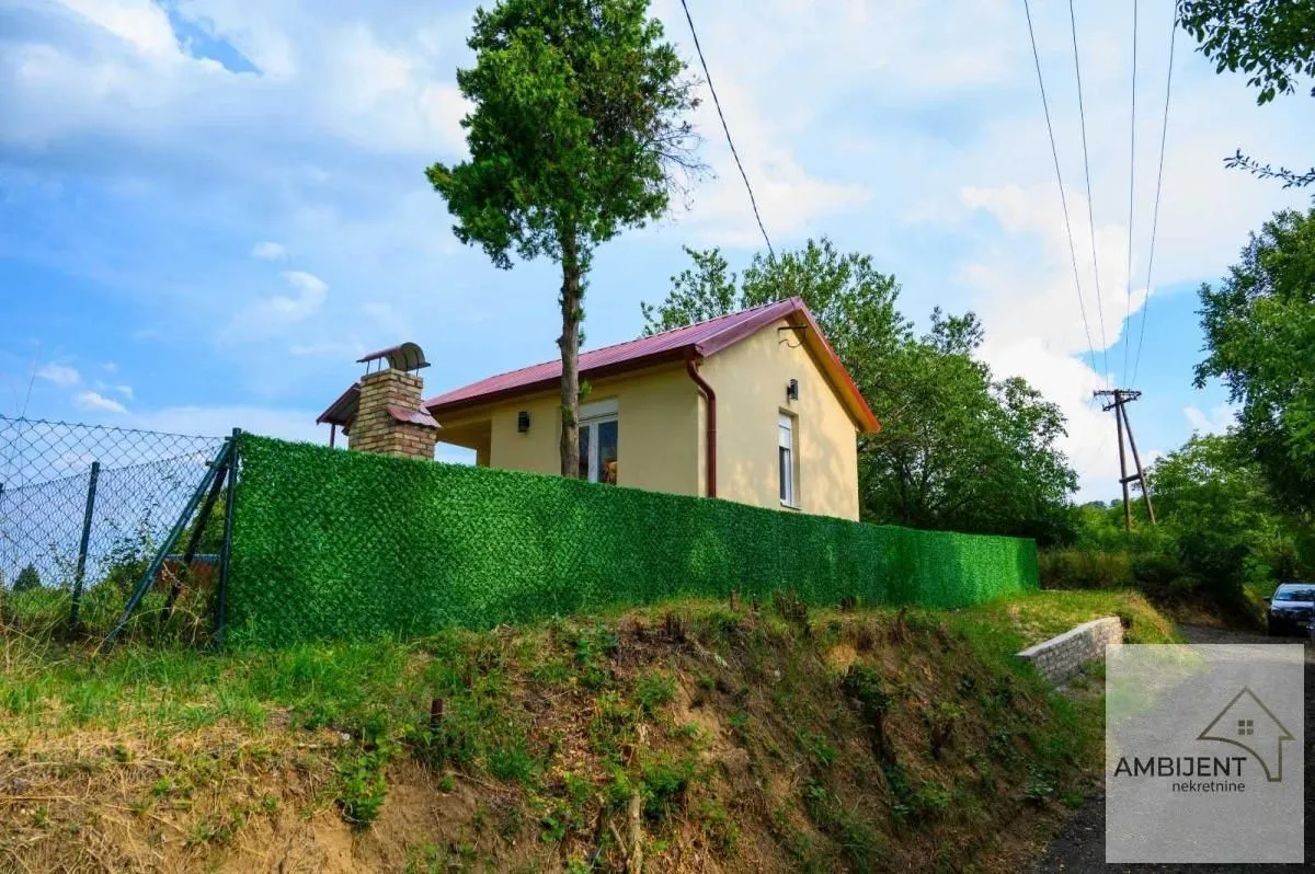 Pogled na kuću sa dvorištem i ogradom.
