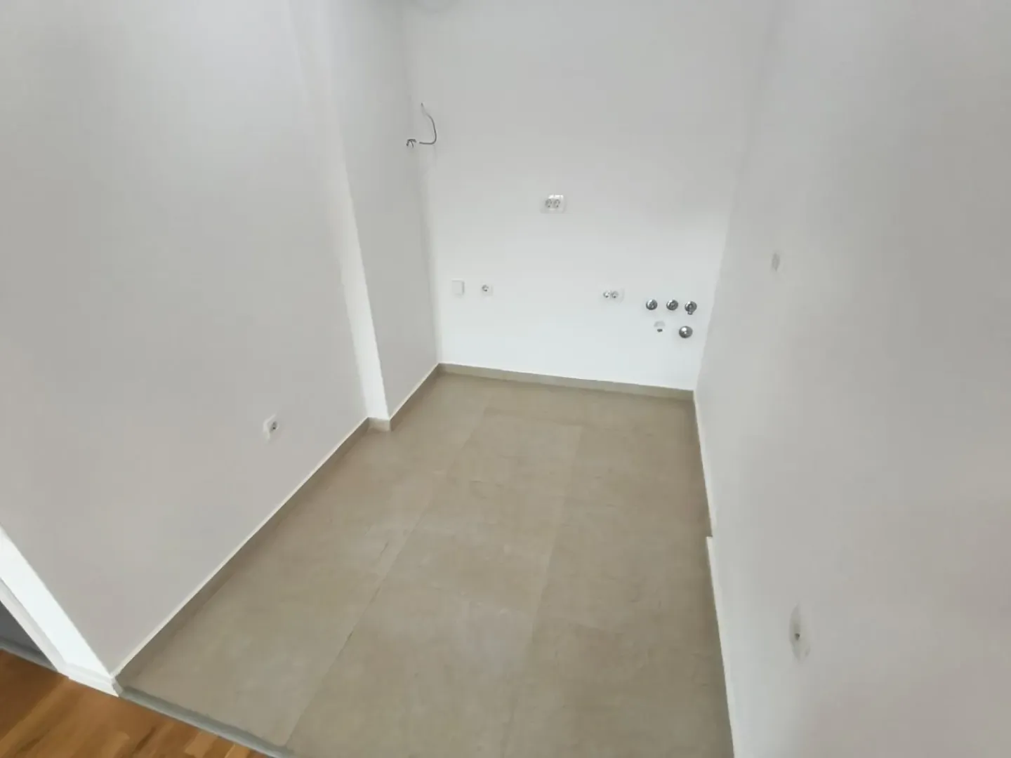 Prazna prostorija sa keramičkim pločicama i instalacijama na zidu.