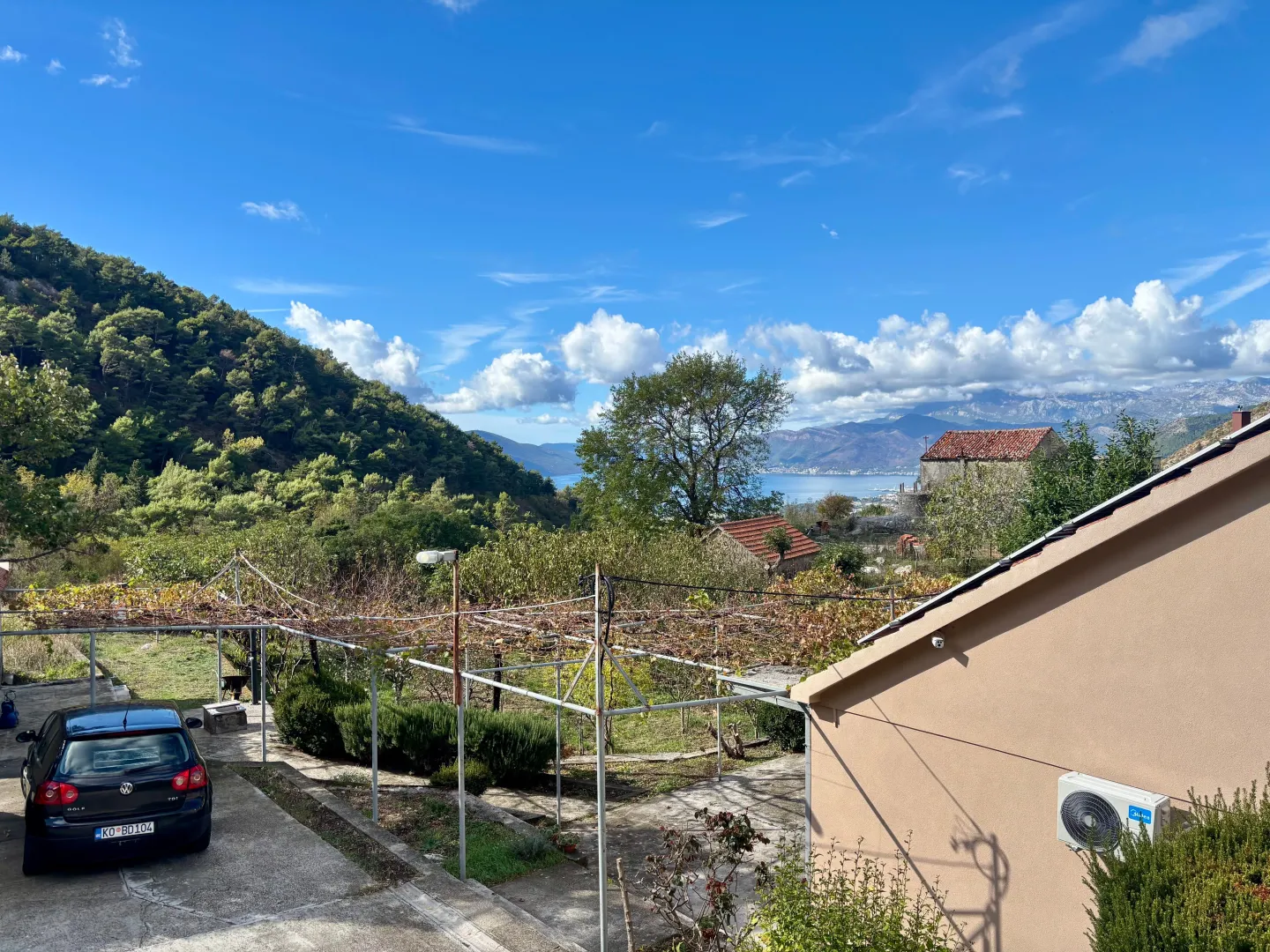 View from the property overlooking the yard, surrounding greenery, and the sea in the distance.