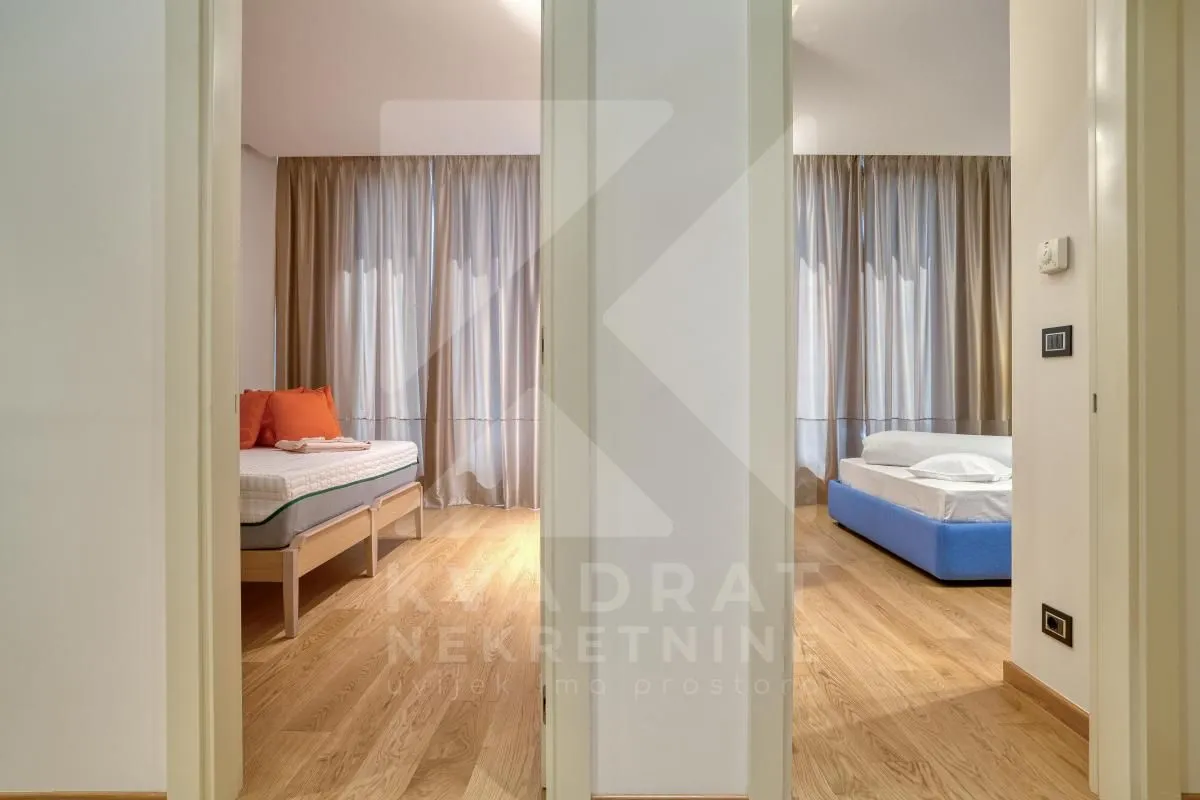 Pogled iz hodnika na dvije spavaće sobe sa drvenim podom.