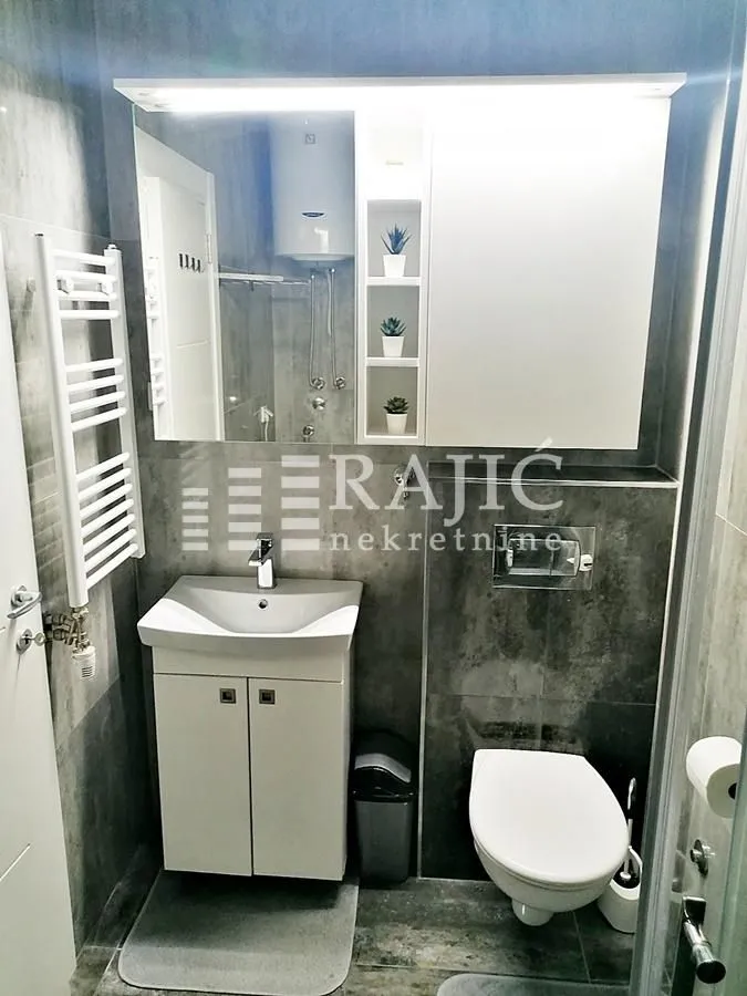 Small bathroom with a sink, toilet, and mirror.
