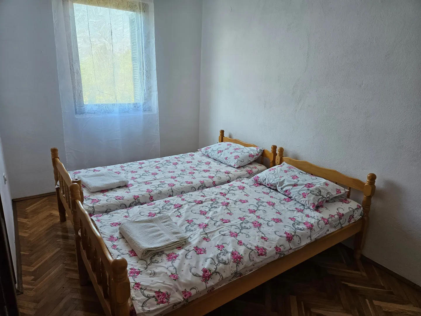 Bedroom with two wooden beds and a window.