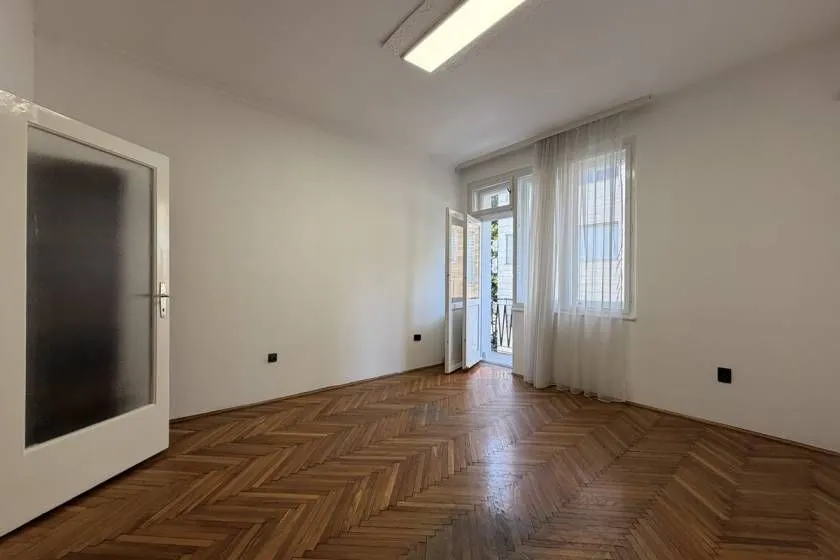 Empty room with parquet flooring and balcony access.