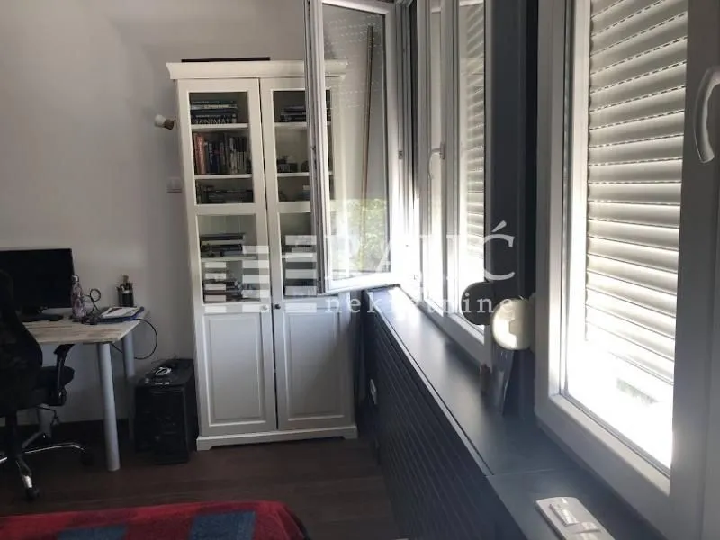 Study room with a white bookcase and desk next to the window.