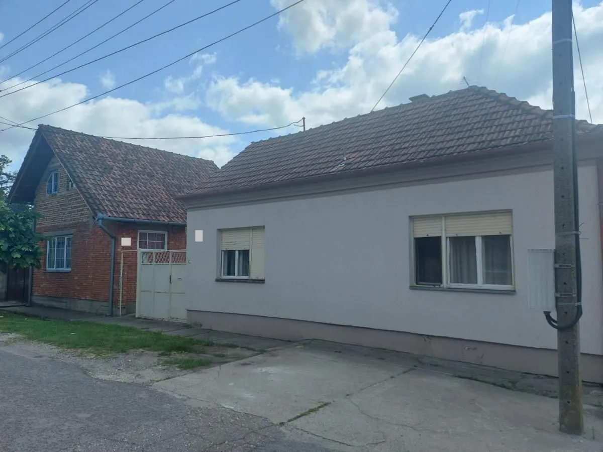 Pogled sa ulice na prizemnu kuću i pomoćni objekat sa krovom od crepa.