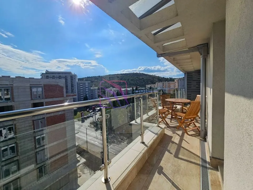 Spacious covered terrace with seating furniture and city view.