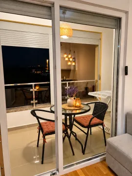 Furnished balcony with a small table and two chairs, offering a night view. - image 4