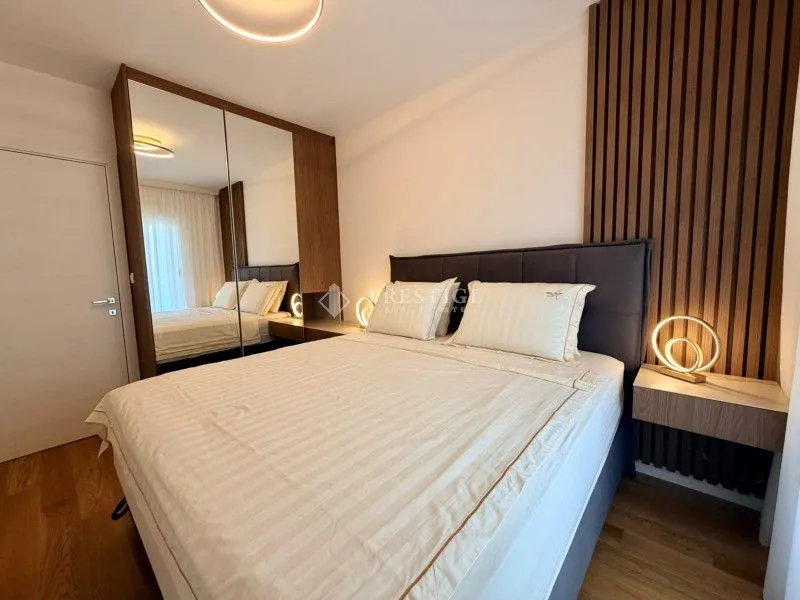 Modern bedroom with a double bed, large mirrored wardrobe, and wooden wall panels.