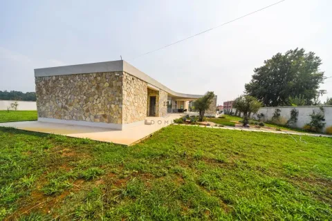 Exterior of a modern ground-floor house with a stone facade and landscaped yard. - image 6