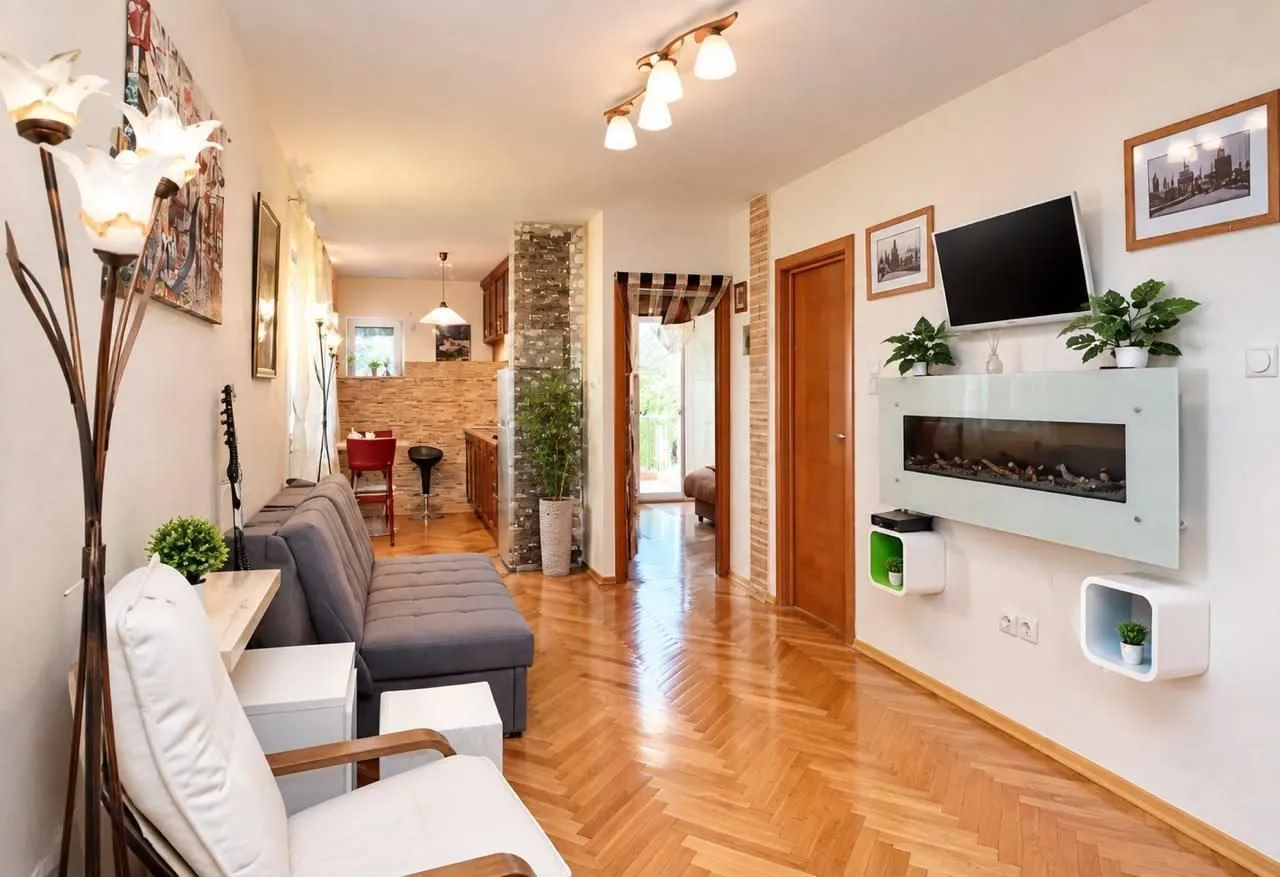 Living room with a sofa, TV, and a view of the kitchen in the background.