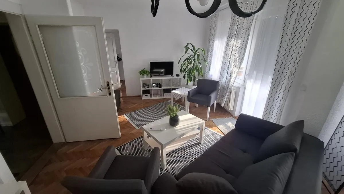 Dnevna soba sa garniturom za sedenje, stočićem i televizorom.
