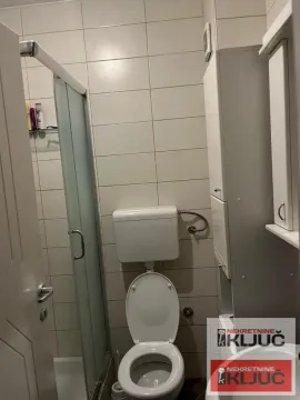 Small bathroom with a toilet, shower cabin, and white cabinet. - image 7