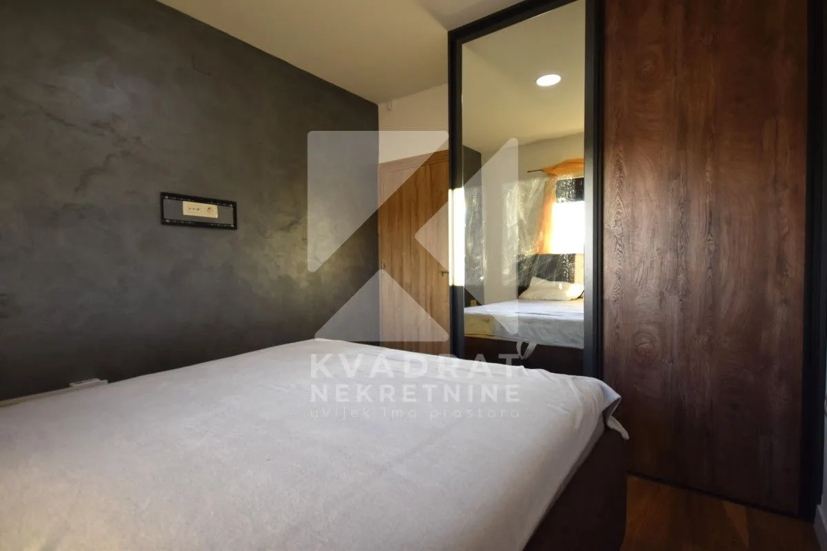 Furnished bedroom with a double bed and a built-in wardrobe with a mirror.