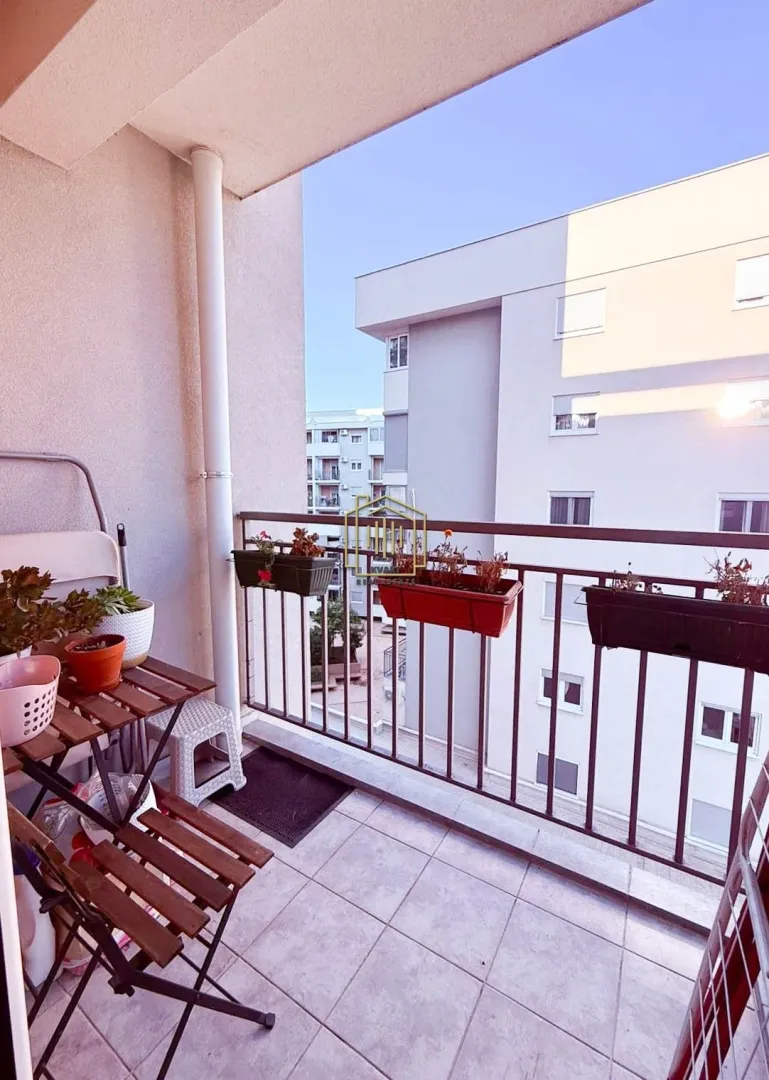 Small balcony with a wooden table and flower pots.