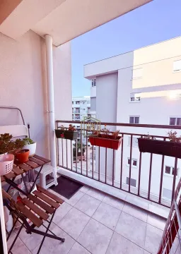 Small balcony with a wooden table and flower pots. - image 5