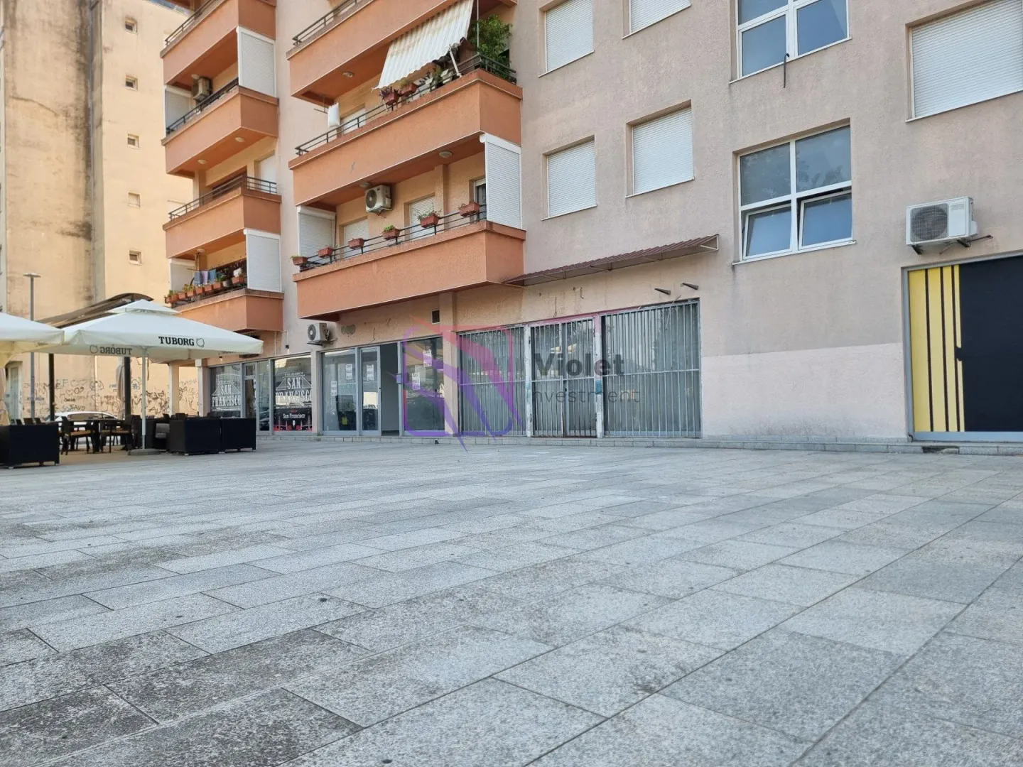 View of the paved plateau in front of a residential and commercial building with balconies.