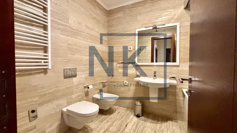 Bathroom covered with ceramic tiles featuring a sink, toilet, and bidet.