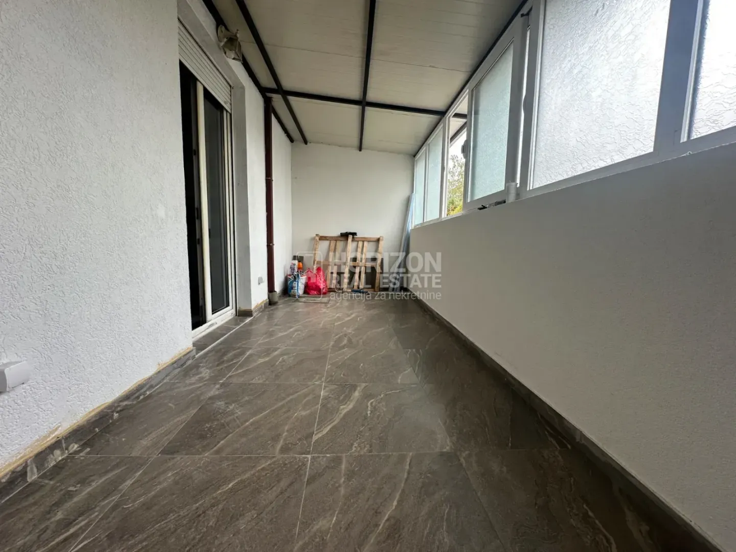Enclosed terrace with tiled floor and white walls.