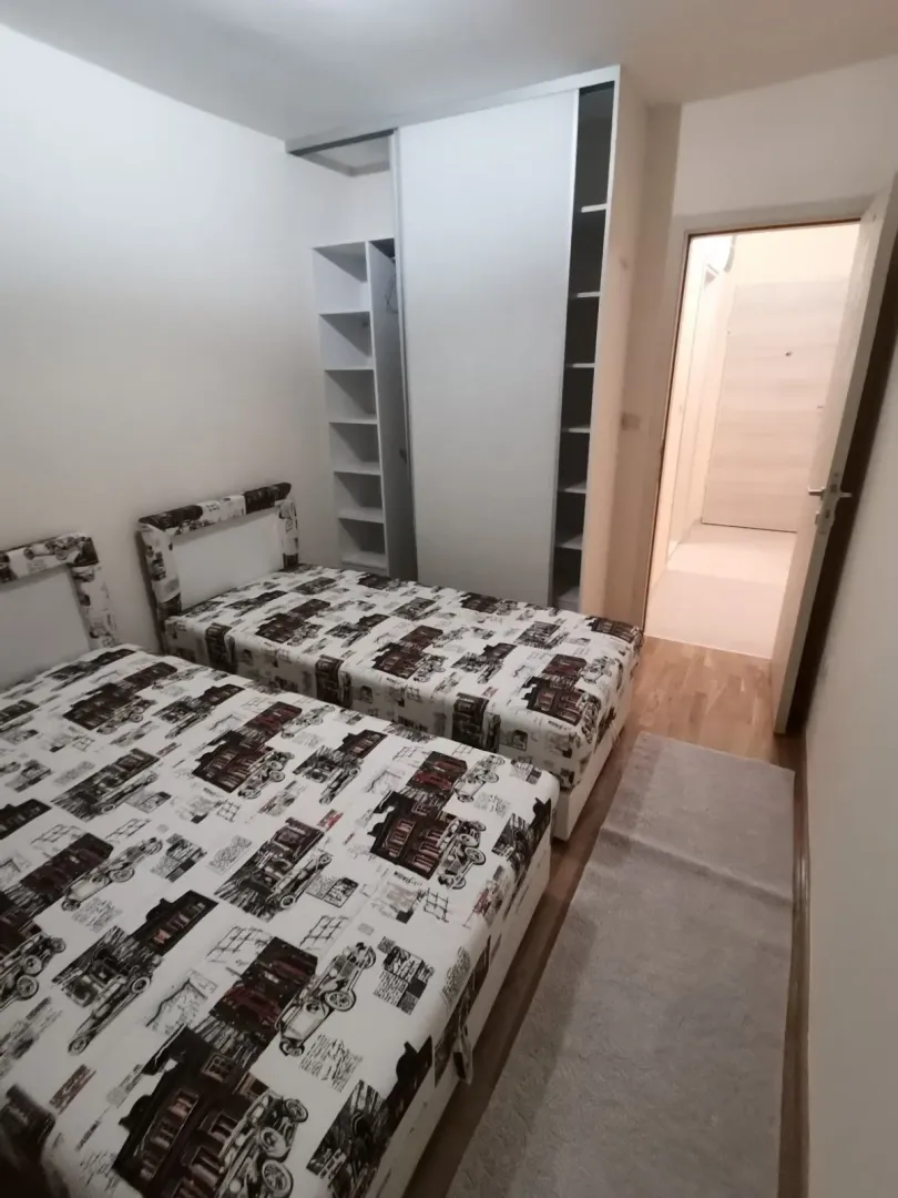 Svijetla spavaća soba sa dva singl kreveta i ormarom.