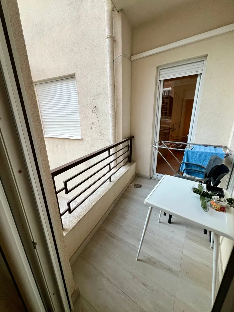 Small balcony with a table, chairs, and a drying rack.