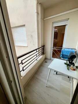 Small balcony with a table, chairs, and a drying rack. - image 12