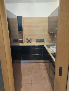 Pogled na manju kuhinju sa crnim elementima i drvenim detaljima kroz vrata. - image 3