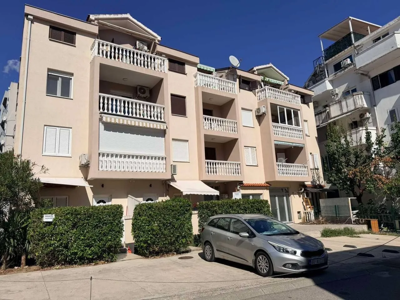 Exterior view of a multi-story residential building with parking in front.