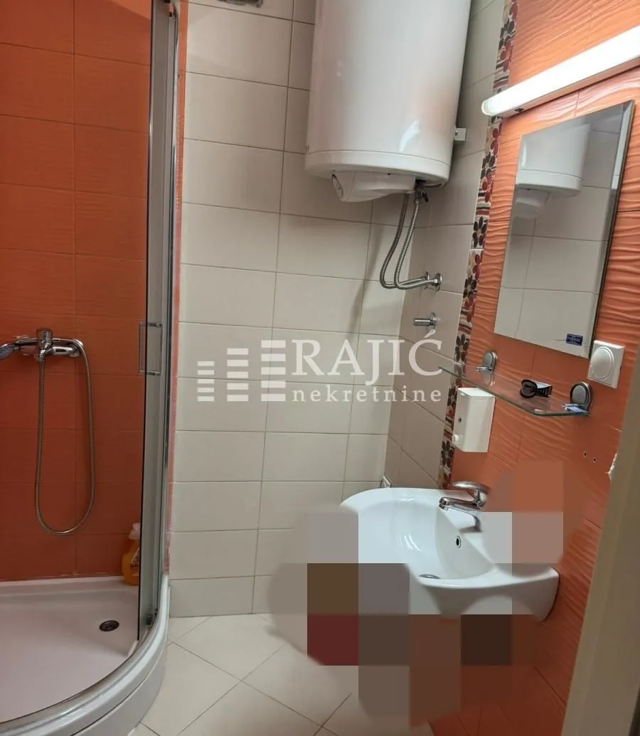 Smaller bathroom with a shower cabin, washbasin, and water heater.